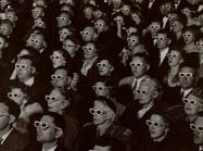 Audience watches movie wearing 3-D spectacles, 1952