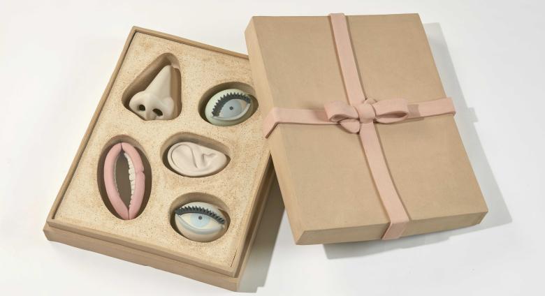 Genesis Belanger ceramic sculpture of a box of chocolate with facial features instead of chocolates