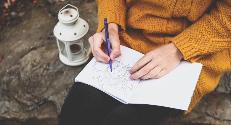 a photo of a person drawing in a journal