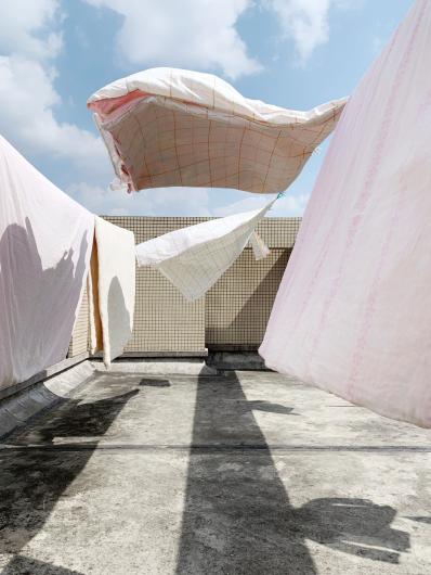 photograph of sheets blowing in the wind, casting shadows on the ground beneath them