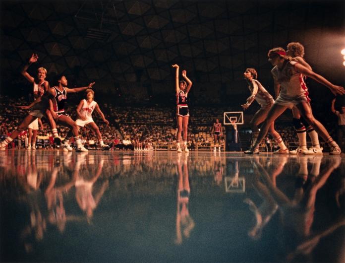 darkly-lit dramatic foul shot as described below. The players all appear twice in the photo as the floor is so reflective.